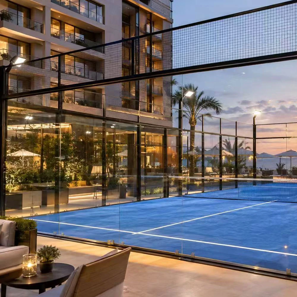 professional outdoor padel court with red artificial turf, black steel fencing, glass panels, and integrated led lighting.